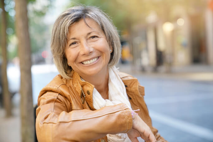 Smiling woman outside sitting on a bench